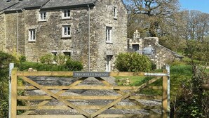 A stone building with a wooden gate labeled "Tregrylls Barton."