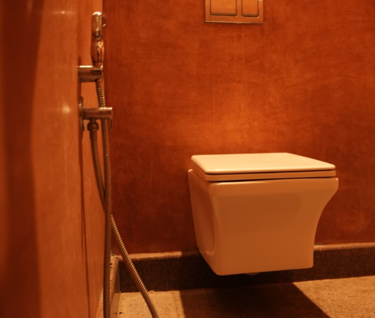 Un baño con inodoro blanco, ducha y puerta de madera.