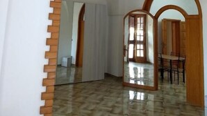 An interior with arched doorways, a tiled floor, and a dining area with chairs and a table. - Salento Relax Cinzia Room (Collepasso)