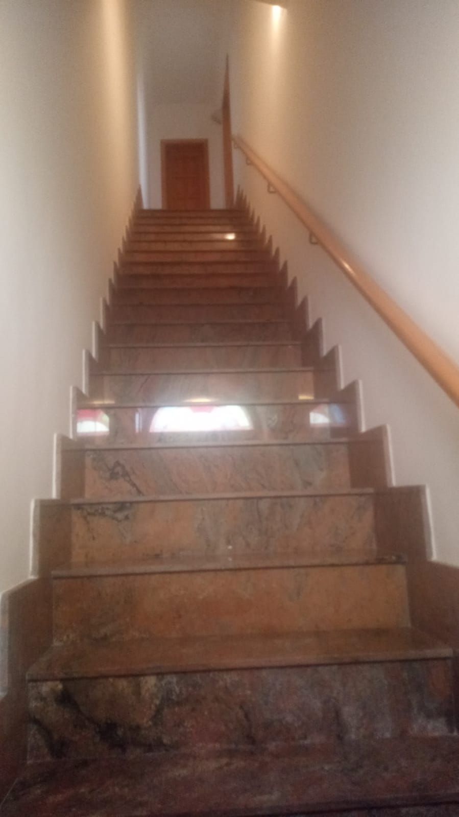 A staircase with a wooden handrail and a marble finish.