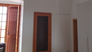A room with a high arched ceiling, a wooden door, a window, and a tiled floor. - Salento Relax Cinzia Room (Collepasso)