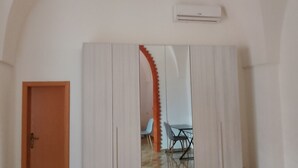 A room with a wooden door, a white wardrobe, a dining table with chairs, and an arched ceiling. - Salento Relax Cinzia Room (Collepasso)