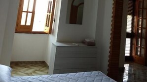 A bedroom with a bed, a dresser, a window, and an arched doorway. - Salento Relax Cinzia Room (Collepasso)