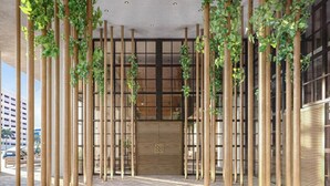 A modern building entrance with vertical bamboo poles and green plants. - Stylish Downtown Miami Studio | Bay Views & Prime Location (Miami)