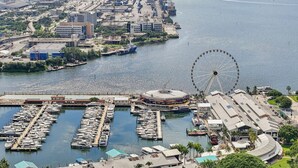 A marina with boats docked, a Ferris wheel, and a large building with a circular structure. - Stylish Downtown Miami Studio | Bay Views & Prime Location (Miami)