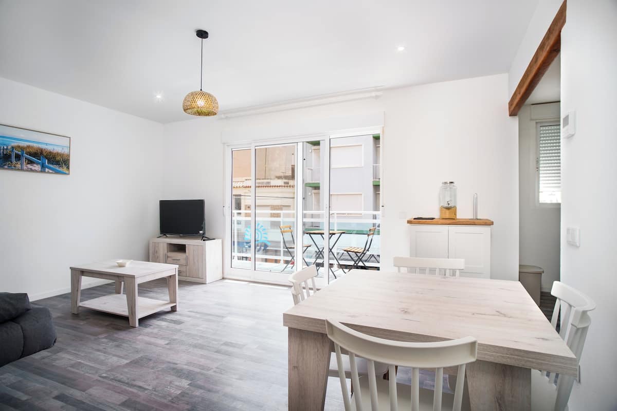 A modern living room with a wooden dining table, a TV, and a sofa.