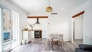 Una cucina moderna con zona pranzo, ampie finestre e un divano grigio.