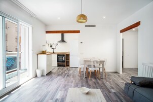 Una cocina moderna con comedor, ventanas amplias y un sofá gris.