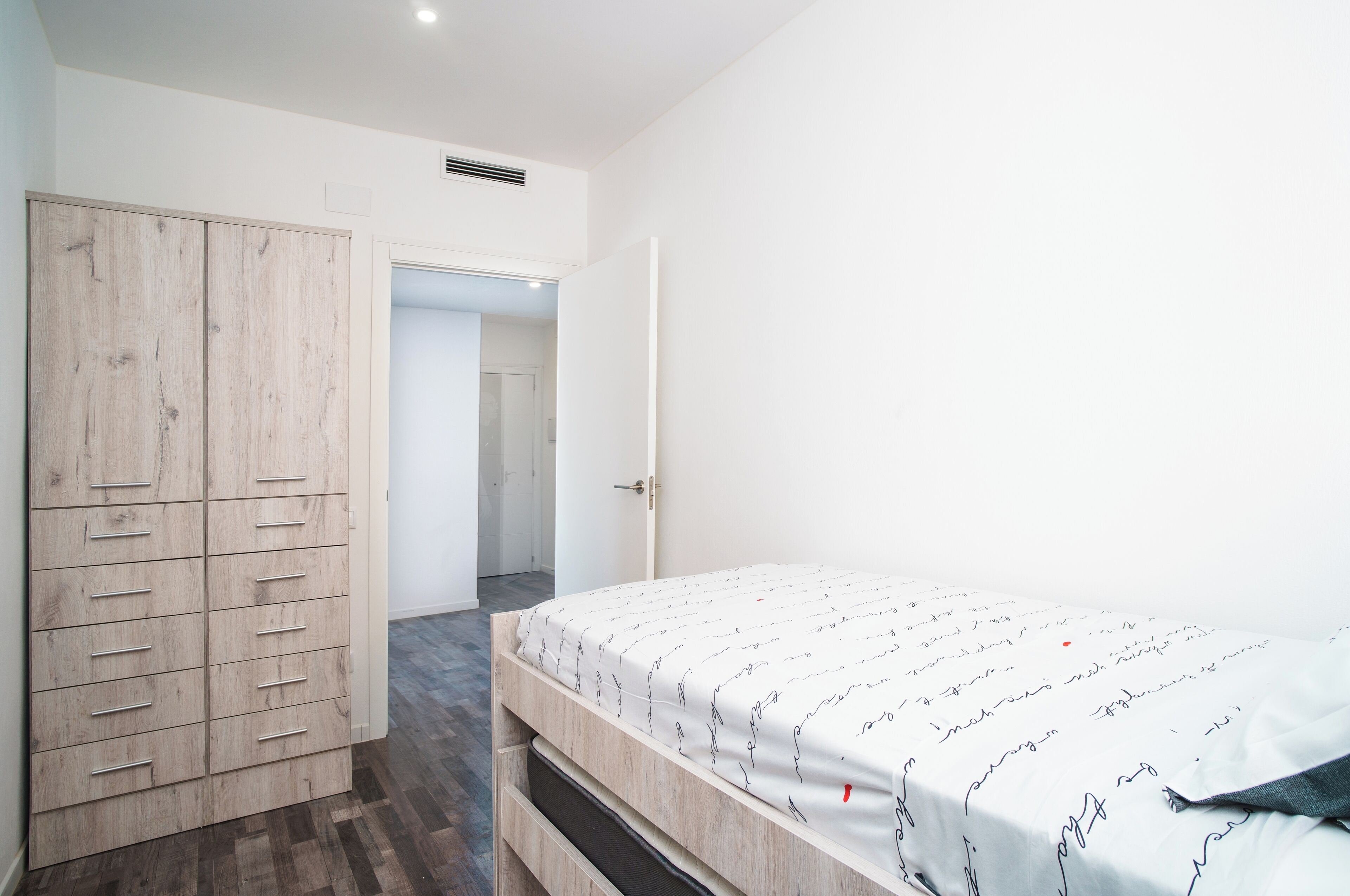 A bedroom with a bed, a wardrobe, and a door leading to another room.