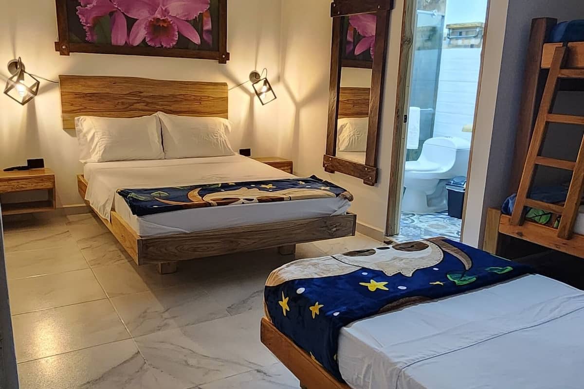 A bedroom with two beds, a wooden headboard, a nightstand, a mirror, and a view of the bathroom.