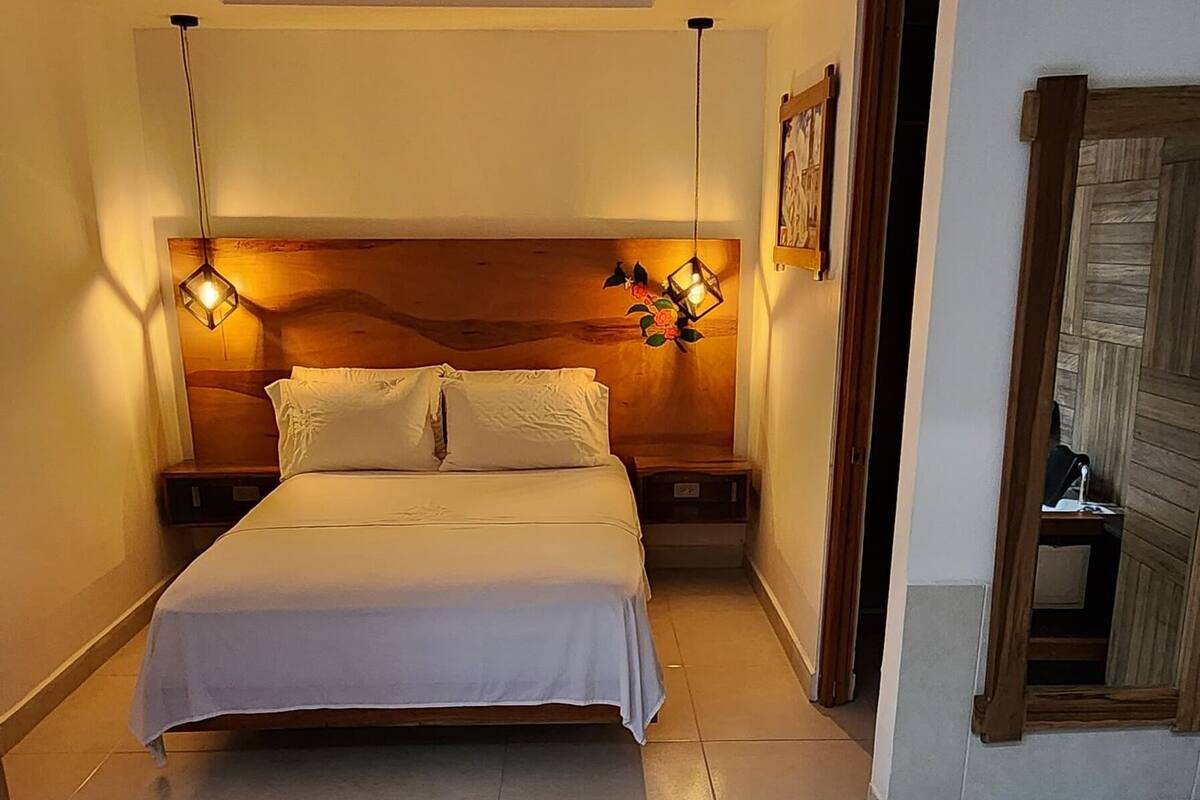 A hotel room with two beds, a wooden headboard, a small table with a towel, and a bathtub.