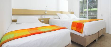 A hotel room with two beds, a large window, and a view of the outdoors.