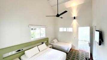 Habitación de hotel con una cama grande, una cama más pequeña, un ventilador de techo, una ventana y una puerta que da a un área exterior.