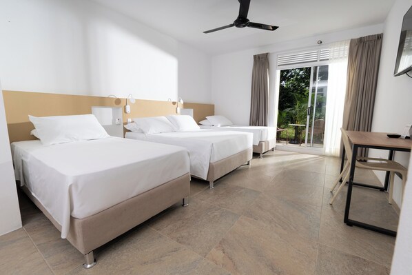 A hotel room with two beds, a desk, and a view of the outdoors. - Hotel Las Palmeras (Villeta)
