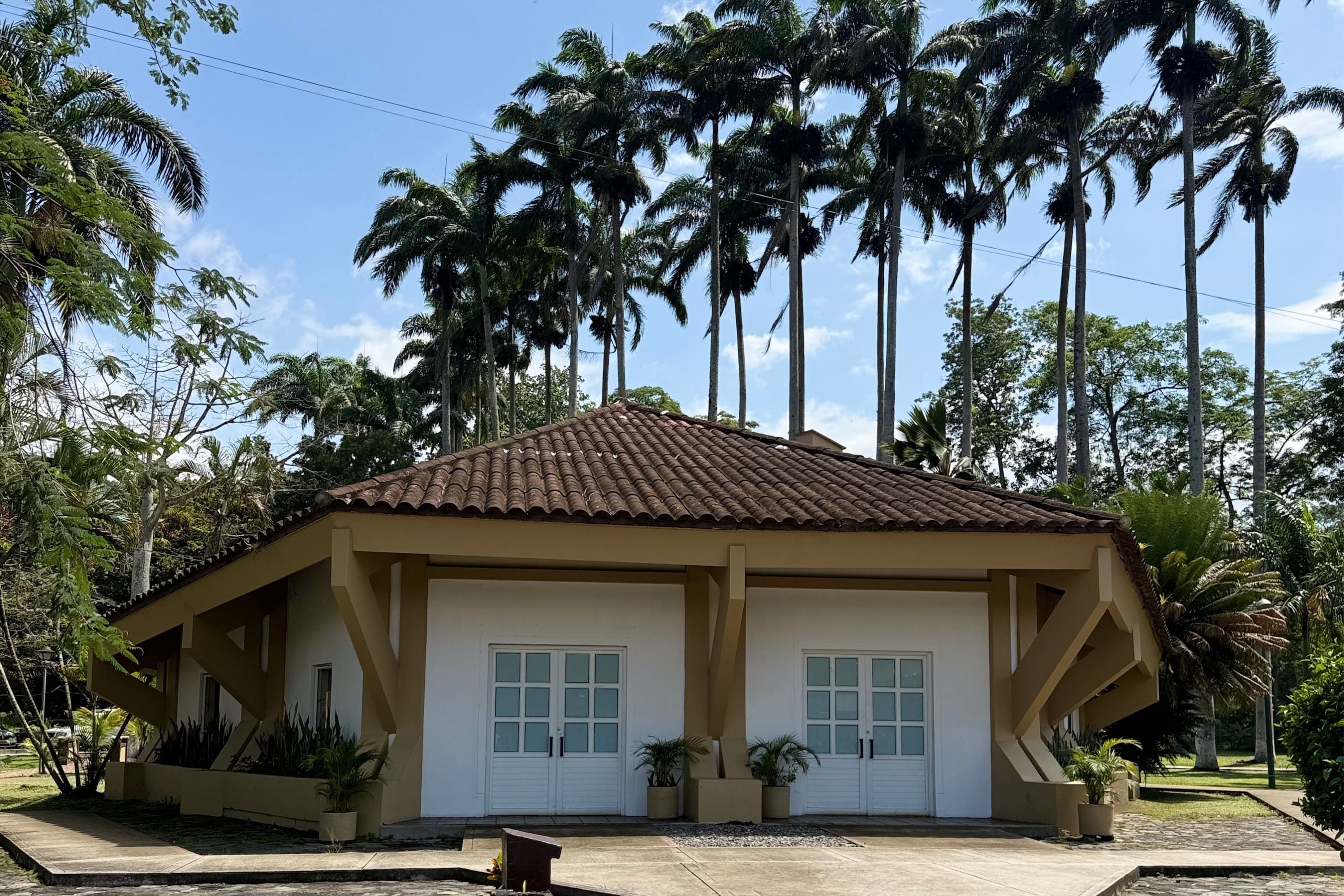 A two-story building with a tiled roof, two white doors, and a small porch area with potted plants.
