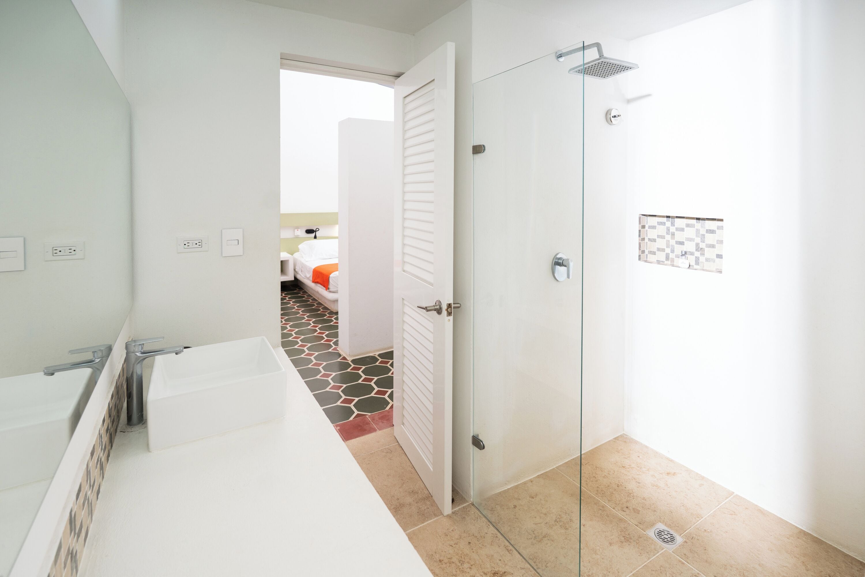 Een moderne badkamer met een glazen douchedeur, een witte wastafel en een betegelde vloer.