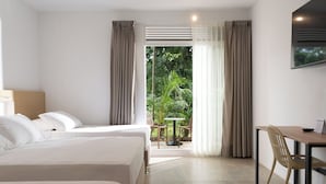 Habitación de hotel con dos camas, un escritorio y vistas a zonas verdes.