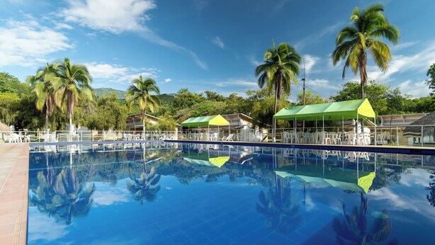Una piscina cristalina que refleja palmeras y un cielo despejado.