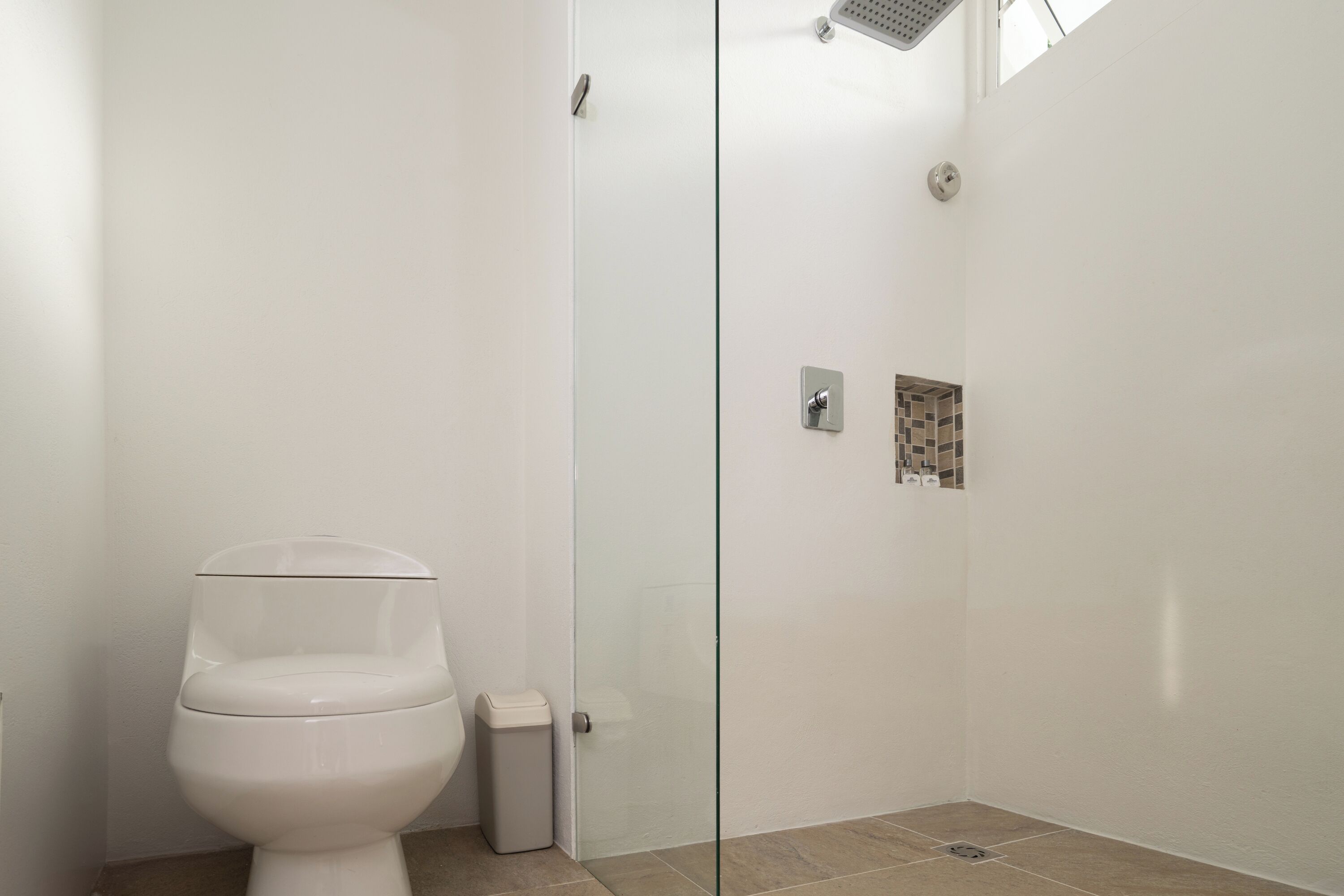 Een moderne badkamer met toilet, een glazen douchecabine en een betegelde douche.