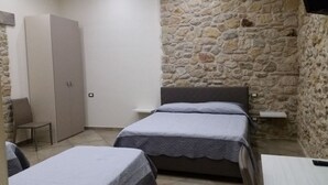 A small, cozy room with two single beds, a chair, a wardrobe, and a stone wall. - La collinettabeb (Bisignano)