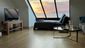 Ein modernes Schlafzimmer im Loft-Stil mit einem großen Oberlicht, einem Bett, einem Fernseher und einem Couchtisch.
