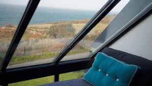 Ein Zimmer mit großem Fenster mit Blick auf eine Küstenlandschaft.