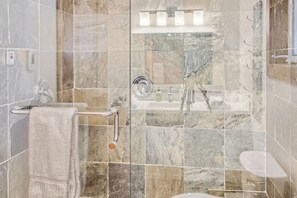 Un baño con cabina de ducha de vidrio, un perchero para toallas y un inodoro.