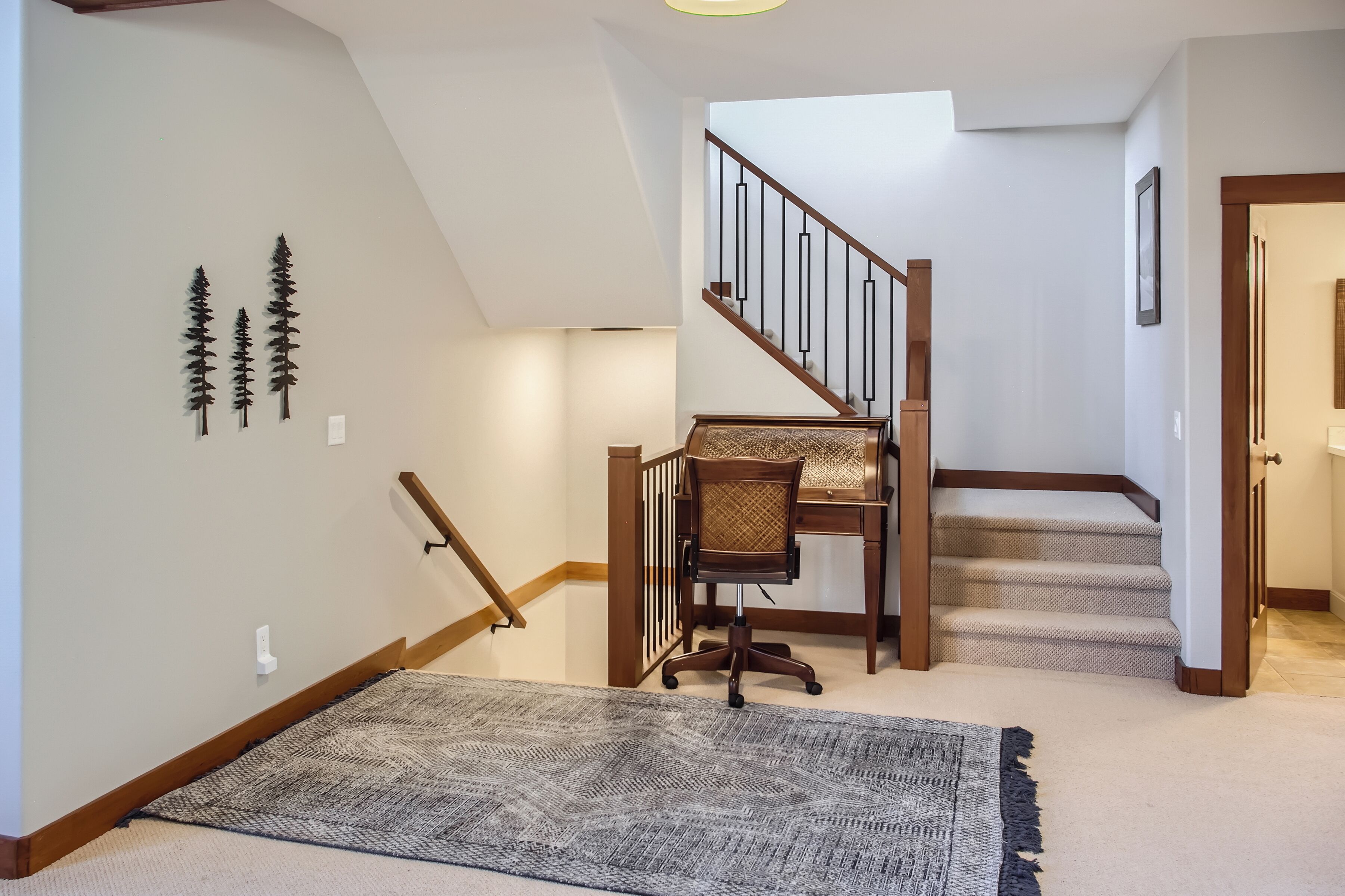 A staircase with wooden railings and carpeted steps, a chair, and wall-mounted decorations.