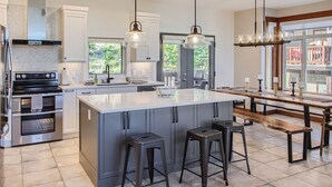 A modern kitchen with a large island, stainless steel appliances, and pendant lighting. -  365 Moonshine Crescent by Okanagan Premier (Beaverdell)