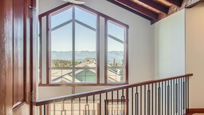 A room with a large window offering a mountain view, a wooden door, and a staircase with a black railing. -  365 Moonshine Crescent by Okanagan Premier (Beaverdell)