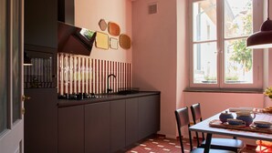 Une cuisine avec des meubles de couleur sombre, une fenêtre et un coin repas comprenant des chaises et une table.