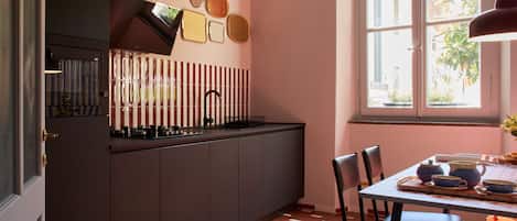 A kitchen with a dark cabinet, a window, and a dining area with chairs and a table.