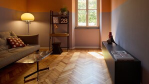 Un salon moderne comprenant un canapé, une table basse, une lampe, une bibliothèque et une fenêtre donnant sur un paysage verdoyant.