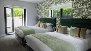 Une chambre double avec deux lits, une porte-fenêtre coulissante donnant sur l’extérieur et une fenêtre avec vue sur la verdure.