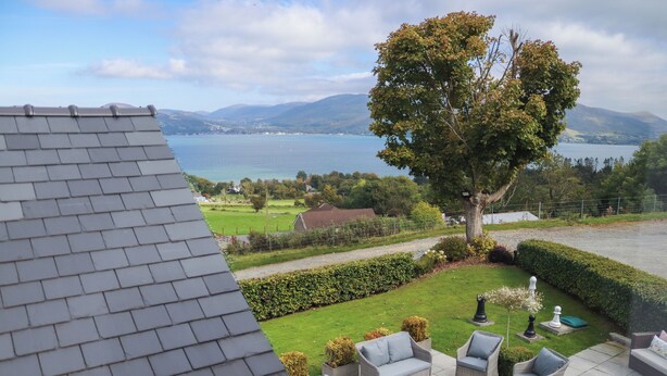 Une terrasse dotée de meubles en osier, offrant une vue sur un lac et des montagnes.