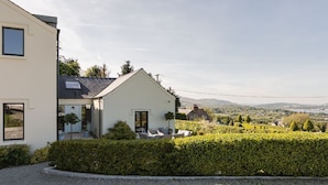 Une maison moderne à deux étages, dotée d’un jardin bien entretenu et offrant une vue dégagée sur le paysage environnant.
