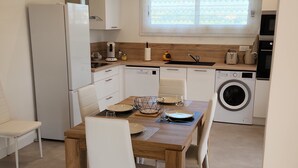 A compact kitchen with a dining table set for four, a washing machine, and a refrigerator. - Coquet 3 Pièces vue mer (Cagnes-sur-Mer)
