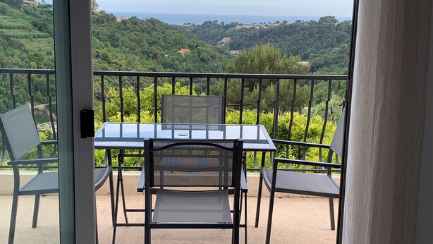 A balcony with a table and chairs, overlooking a lush green landscape and the sea. - Coquet 3 Pièces vue mer (Cagnes-sur-Mer)