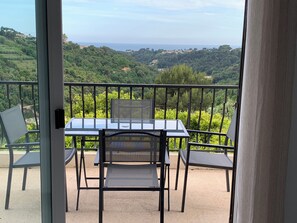 A balcony with a table and chairs, overlooking a lush green landscape and the sea. - Coquet 3 Pièces vue mer (Cagnes-sur-Mer)