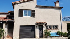 A two-story house with a tiled roof, a garage, and a small porch with a bench. - Coquet 3 Pièces vue mer (Cagnes-sur-Mer)