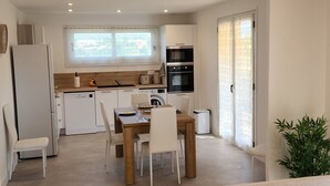 A modern living room with a beige sofa and a dining area with a wooden table and chairs. - Coquet 3 Pièces vue mer (Cagnes-sur-Mer)