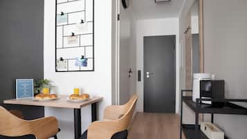 Una cucina moderna con un tavolo in legno, due sedie, una macchina da caffè e una bacheca a parete.