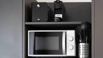 A kitchen with a microwave, a coffee maker, and a utensil holder.