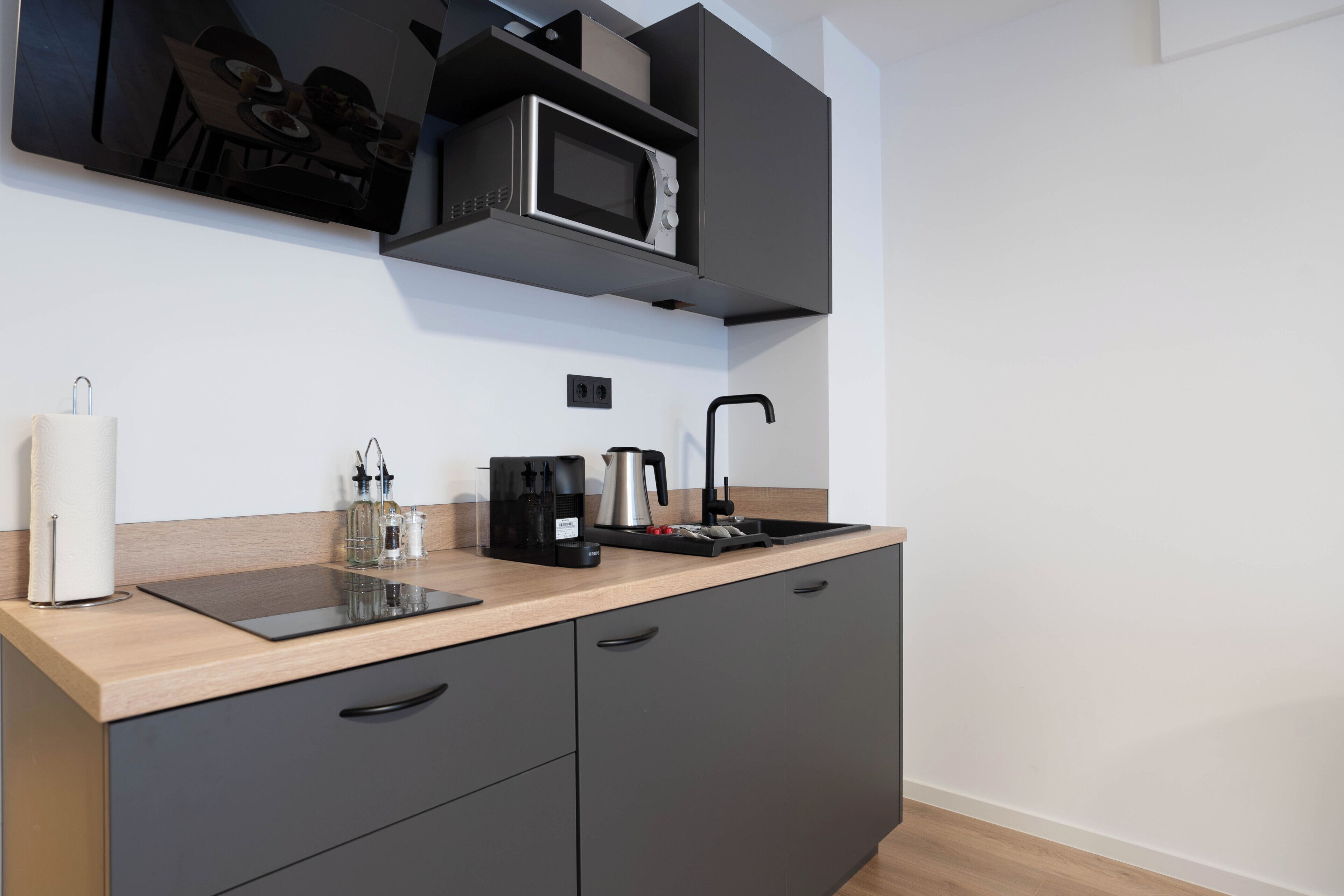 A modern kitchen with a built-in microwave, coffee maker, and a sink.