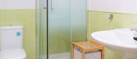 Un baño con ducha de vidrio, inodoro y lavamanos.