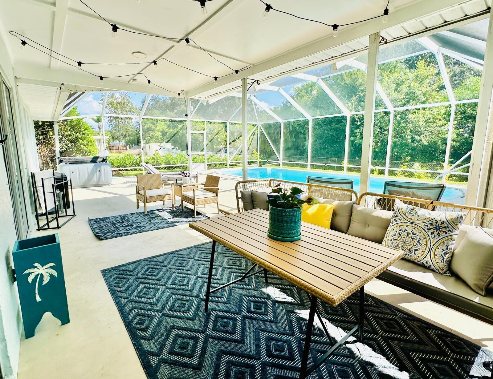 A sunroom with a glass ceiling, a pool, wicker furniture, and a patterned rug.