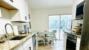 A modern kitchen with white cabinets, a granite countertop, and a large window.