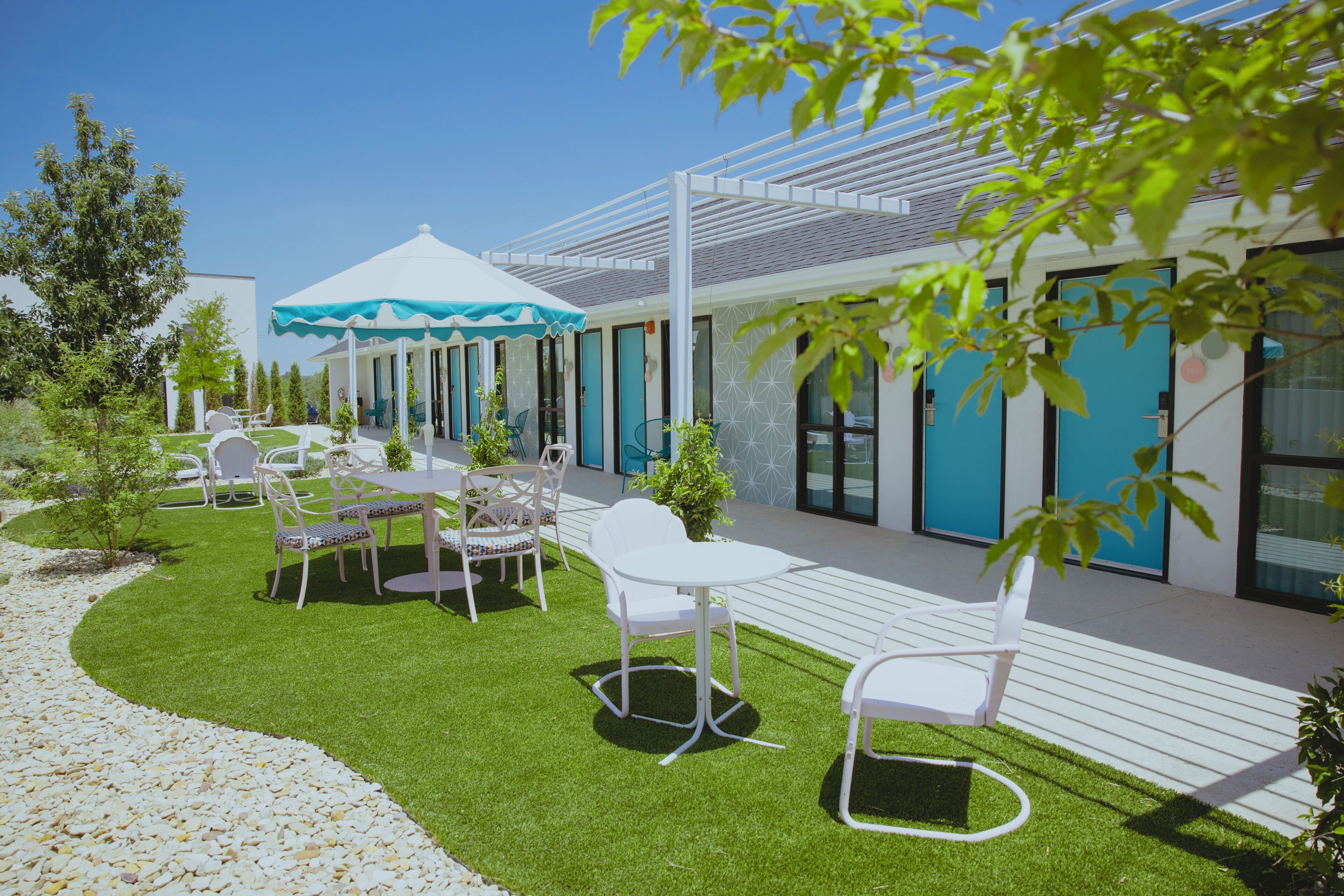 Un espace patio avec des sièges extérieurs, un coin salon abrité et un bâtiment avec des portes bleues.
