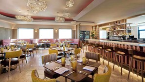 A restaurant with multiple dining areas, including a bar and seating with tables and chairs. - Interstate Inn (Stephenville)