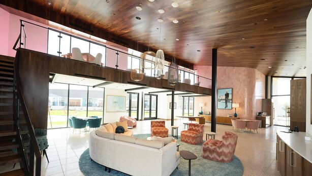 A spacious living area with a high ceiling, a staircase, and a view of the outdoors. - Interstate Inn (Stephenville)